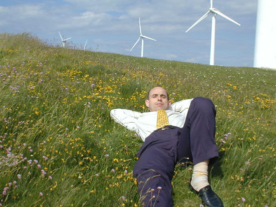 Bruno
        Comby faisant la sieste dans un champ d'oliennes, Bruno Comby,
        sleeping in a field of windmills, (c) Bruno Comby institute